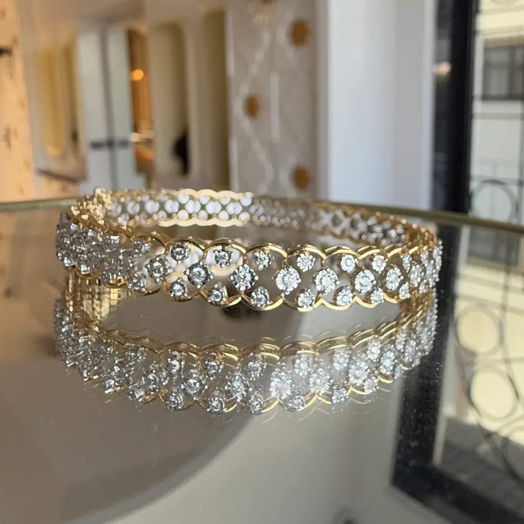 A luxurious diamond gold tennis bracelet with openable sections, featuring gold color and adorned with genuine diamonds, displayed on a glass.