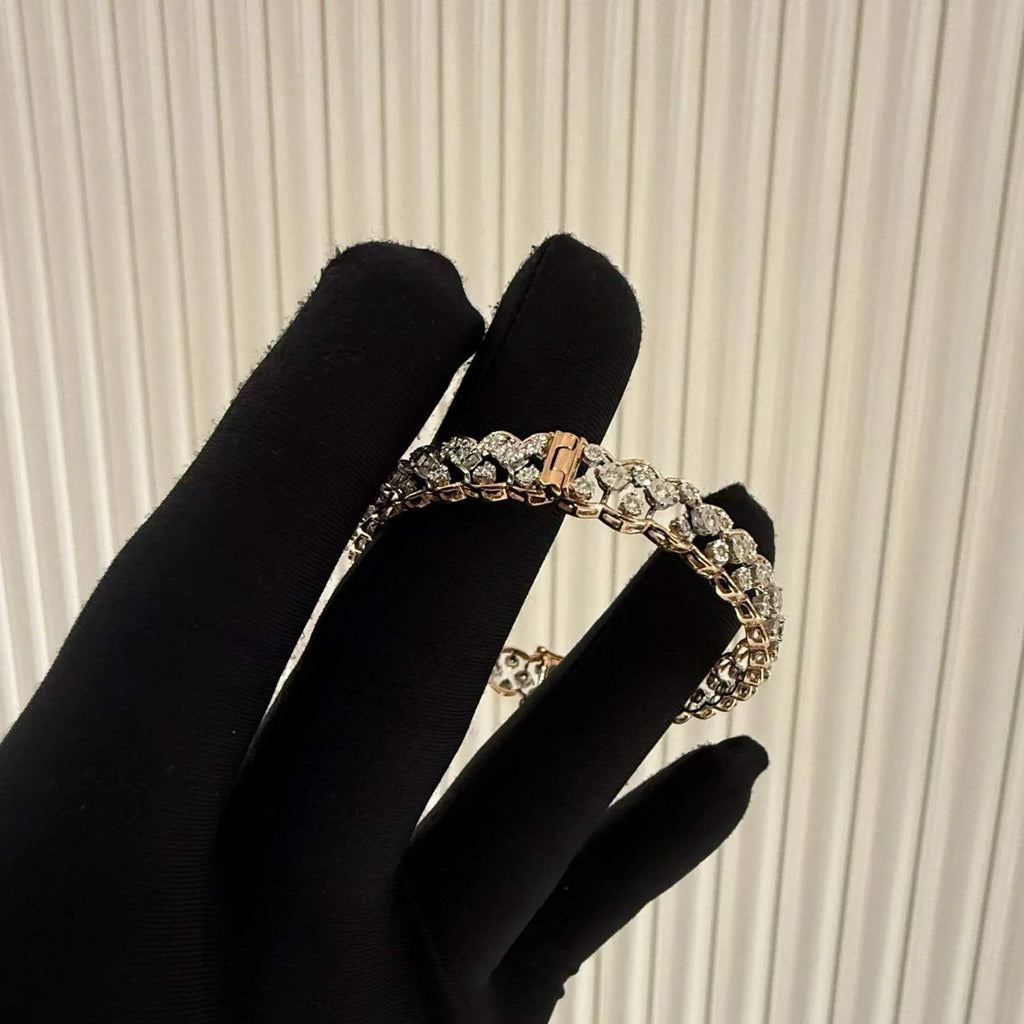 A luxurious diamond gold tennis bracelet with openable sections, featuring gold color and adorned with genuine diamonds, displayed by a hand.