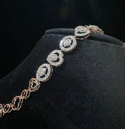 A gold diamond bracelet with oval heart shapes, displayed on a black mannequin.