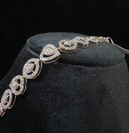 A gold diamond bracelet with oval heart shapes, displayed on a black mannequin.