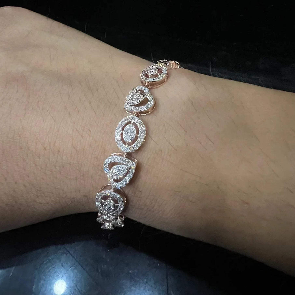 A gold diamond bracelet with oval heart shapes, displayed on a black mannequin.