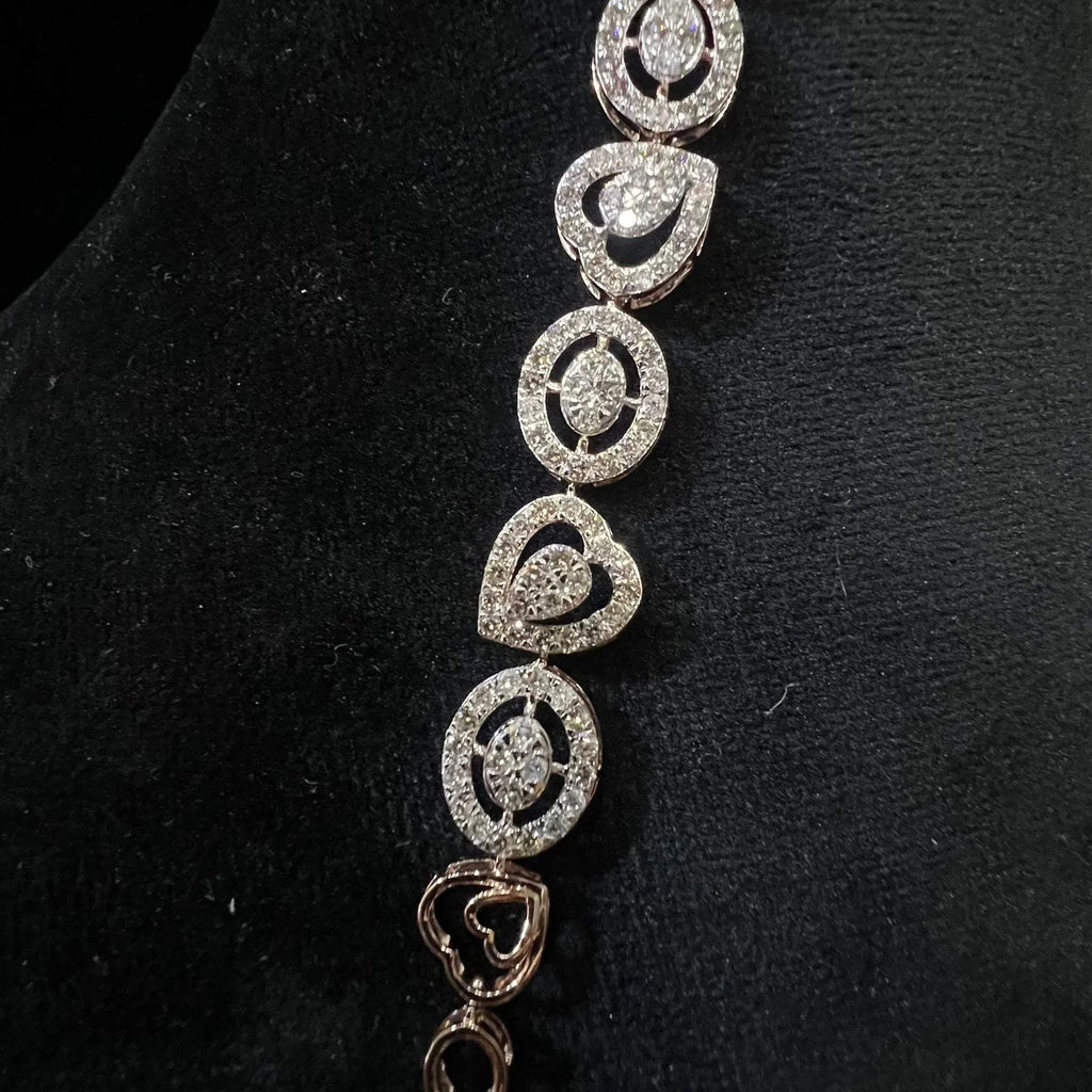 A gold diamond bracelet with oval heart shapes, displayed on a black mannequin.