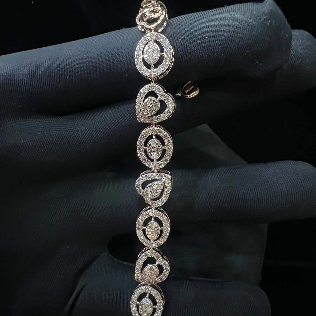 A gold diamond bracelet with oval heart shapes, displayed on a black mannequin hand.