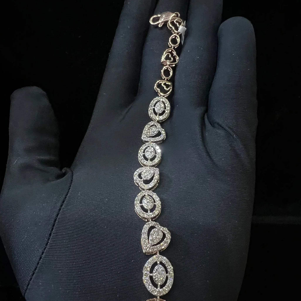 A gold diamond bracelet with oval heart shapes, displayed on a black mannequin hand.