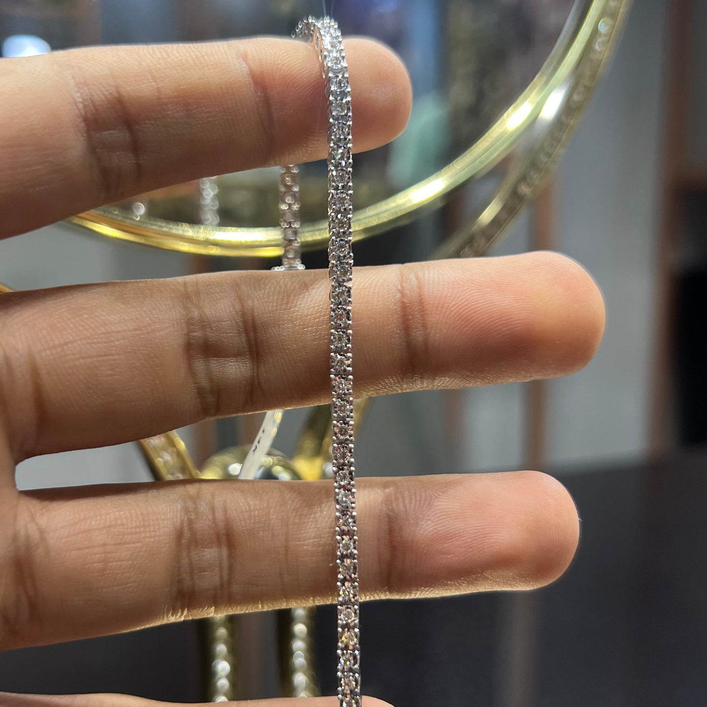 A tennis bracelet featuring a series of linked gold chains adorned with white diamonds, displayed on a hand.
