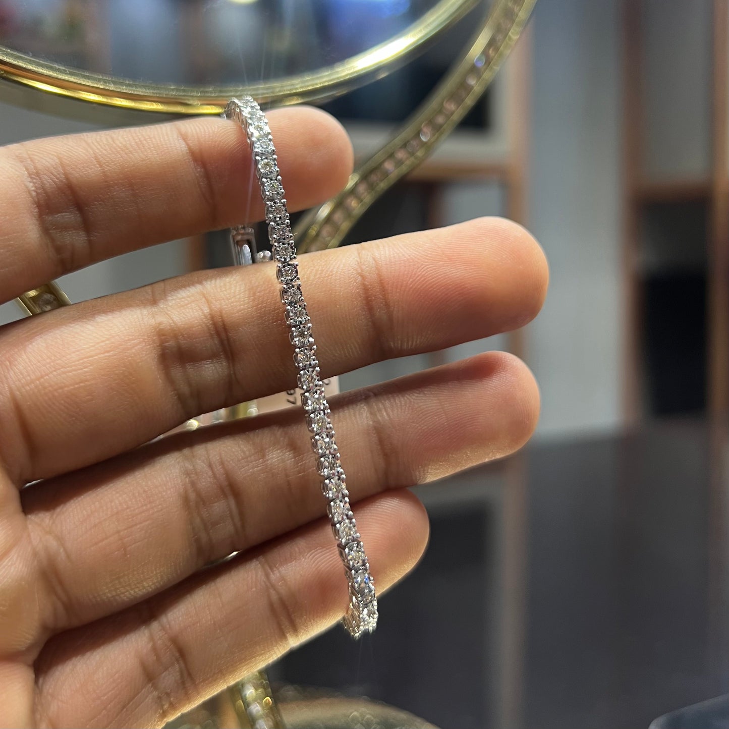 A tennis bracelet featuring a series of linked gold chains adorned with white diamonds, displayed on a hand.