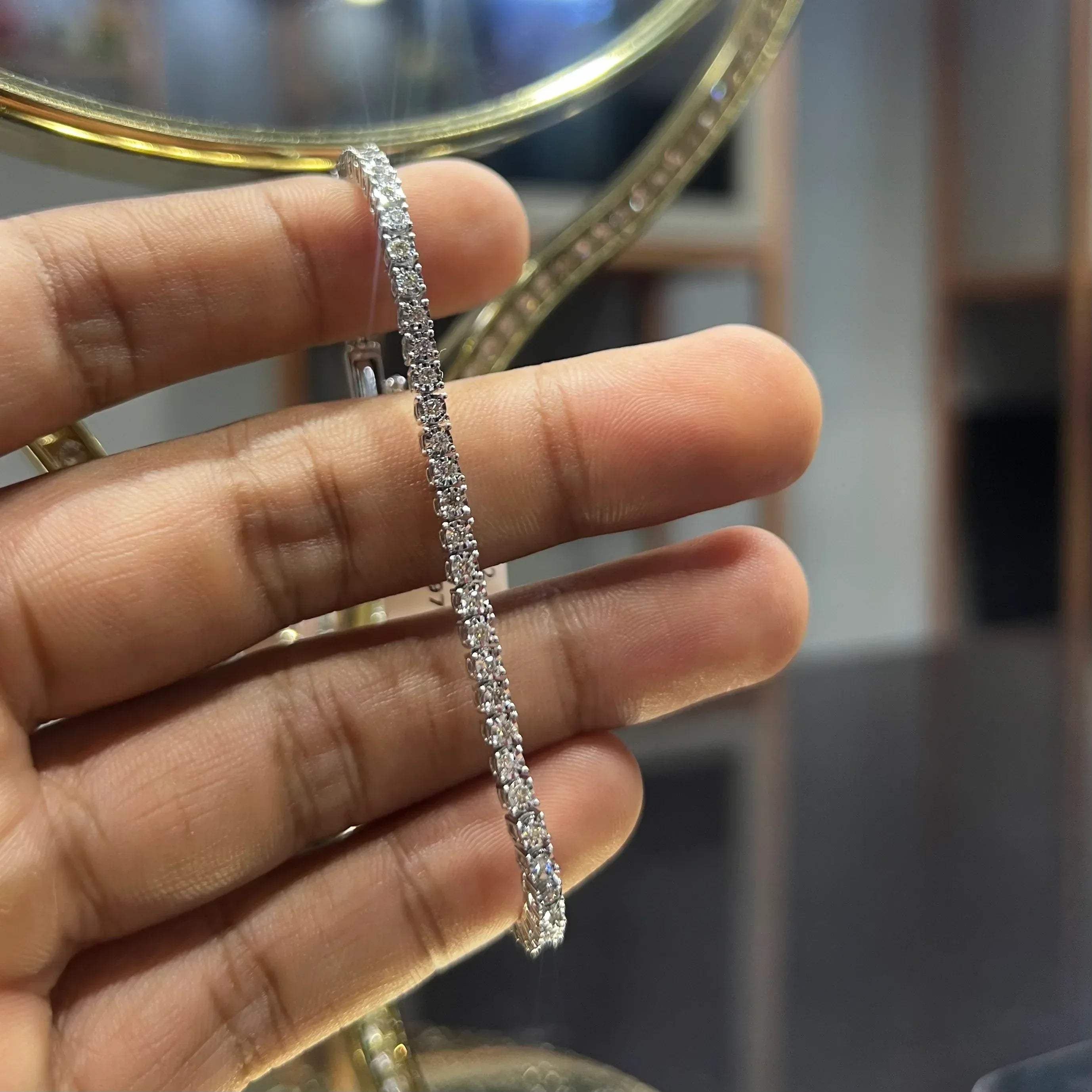 A tennis bracelet featuring a series of linked gold chains adorned with white diamonds, displayed on a hand.