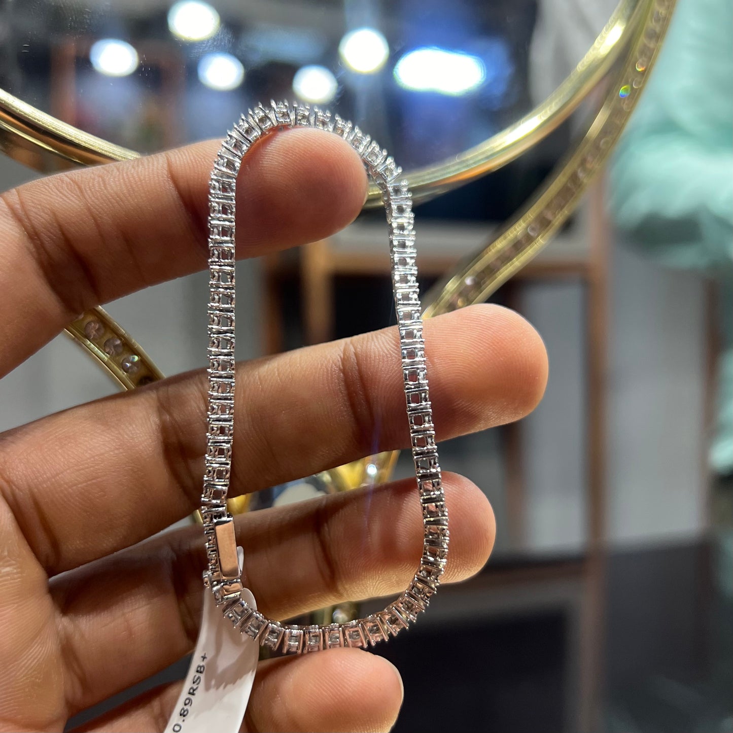 A tennis bracelet featuring a series of linked gold chains adorned with white diamonds, displayed on a hand.