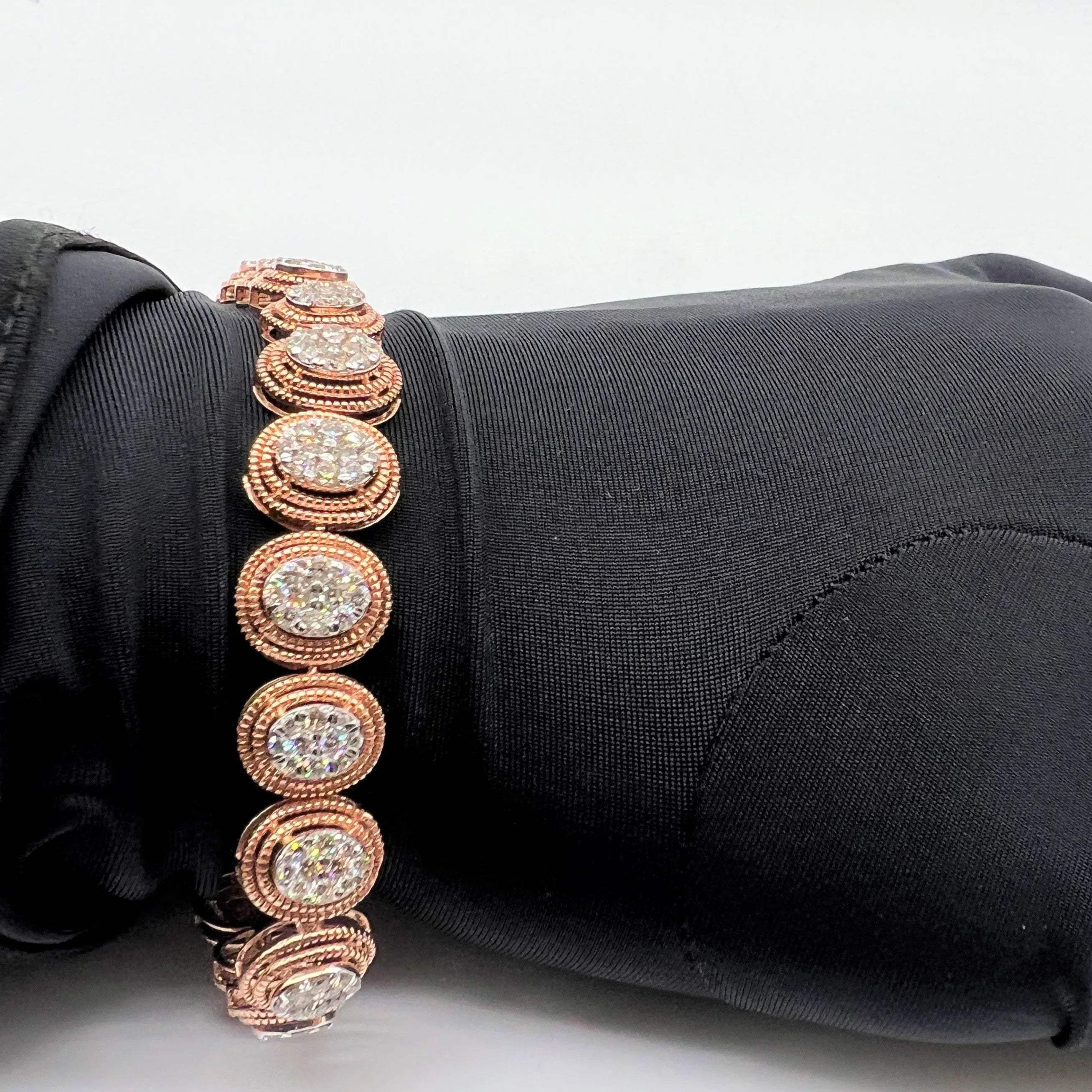A gold diamond bracelet with multiple rows of inset stones, displayed on a mannequin hand.