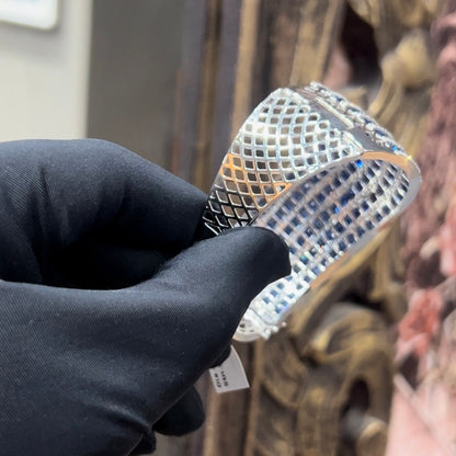 A close-up image of a hand holding a luxurious gold diamond bracelet with a sparkling blue stone, showing an openable design.
