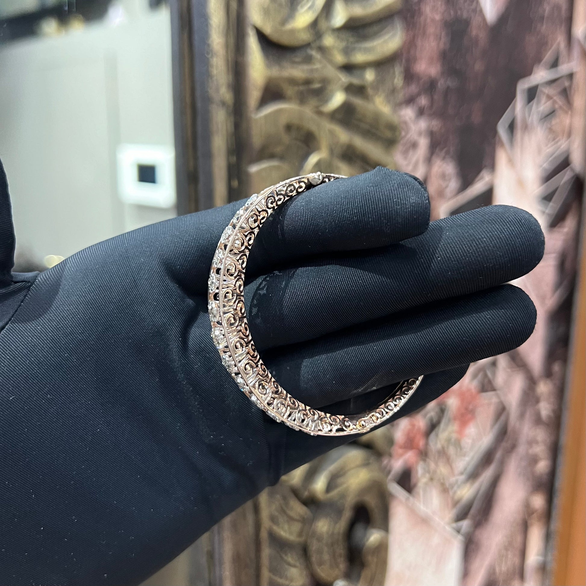 Elegant gold diamond bracelet with round-cut diamonds in a bangle design, displayed on a hand.