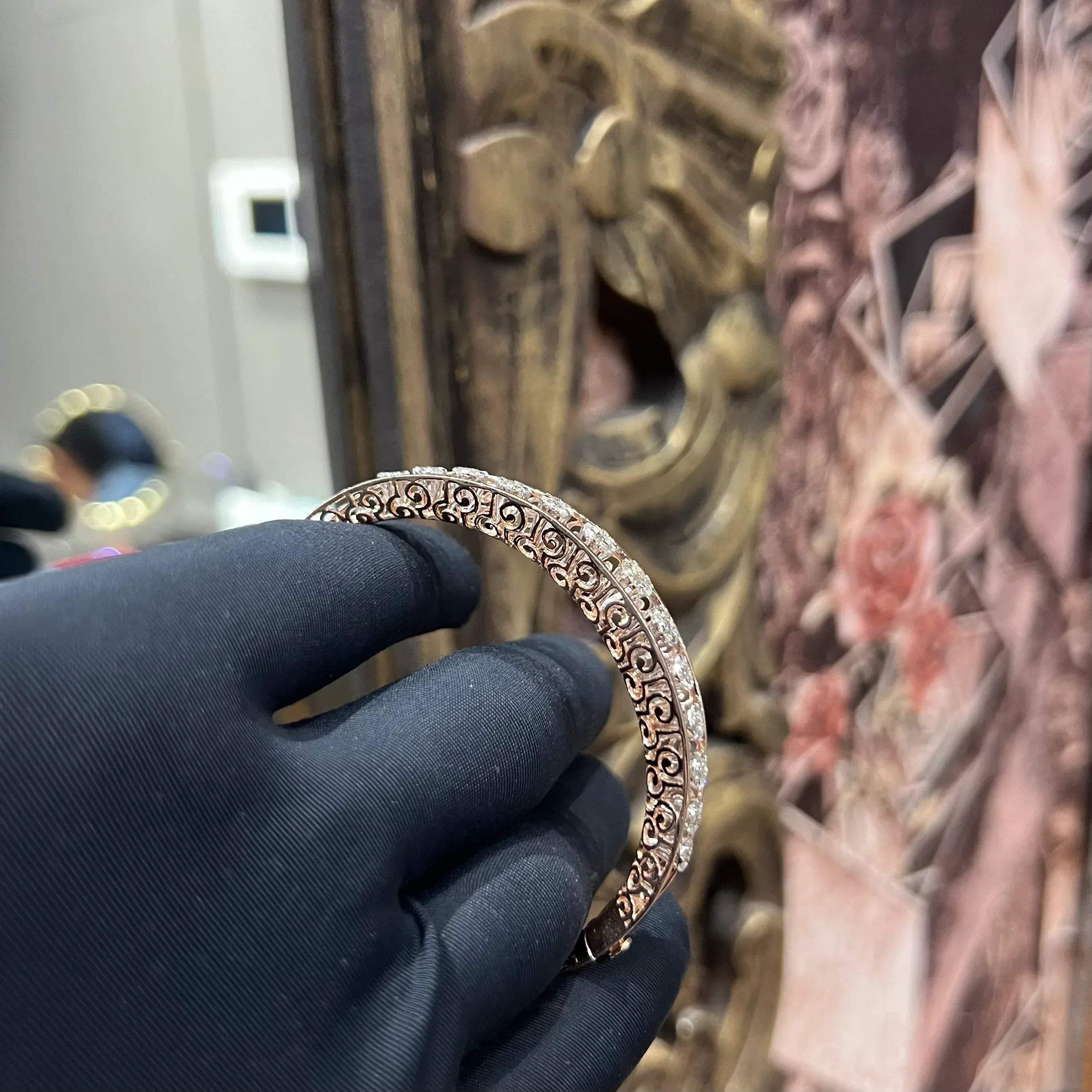 Elegant gold diamond bracelet with round-cut diamonds in a bangle design, displayed on a hand.