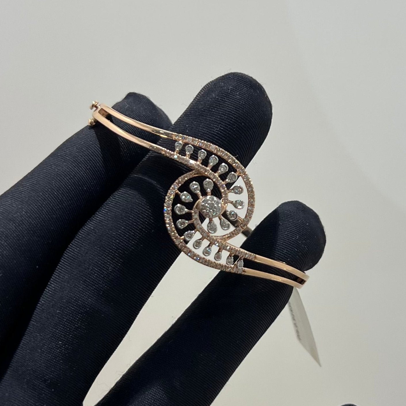 A luxurious gold diamond bracelet with a openable design, featuring a central oval-shaped diamond surrounded by smaller diamonds set in a brilliant cut, displayed on a mannequin hand.