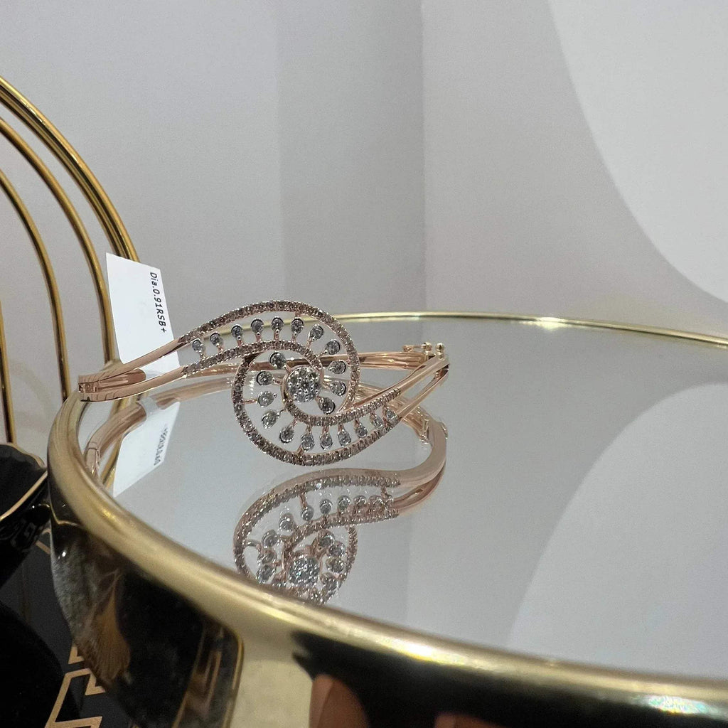 A luxurious gold diamond bracelet with a openable design, featuring a central oval-shaped diamond surrounded by smaller diamonds set in a brilliant cut, displayed on a reflective surface.