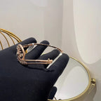 A luxurious gold diamond bracelet with a openable design, featuring a central oval-shaped diamond surrounded by smaller diamonds set in a brilliant cut, displayed on a hand.