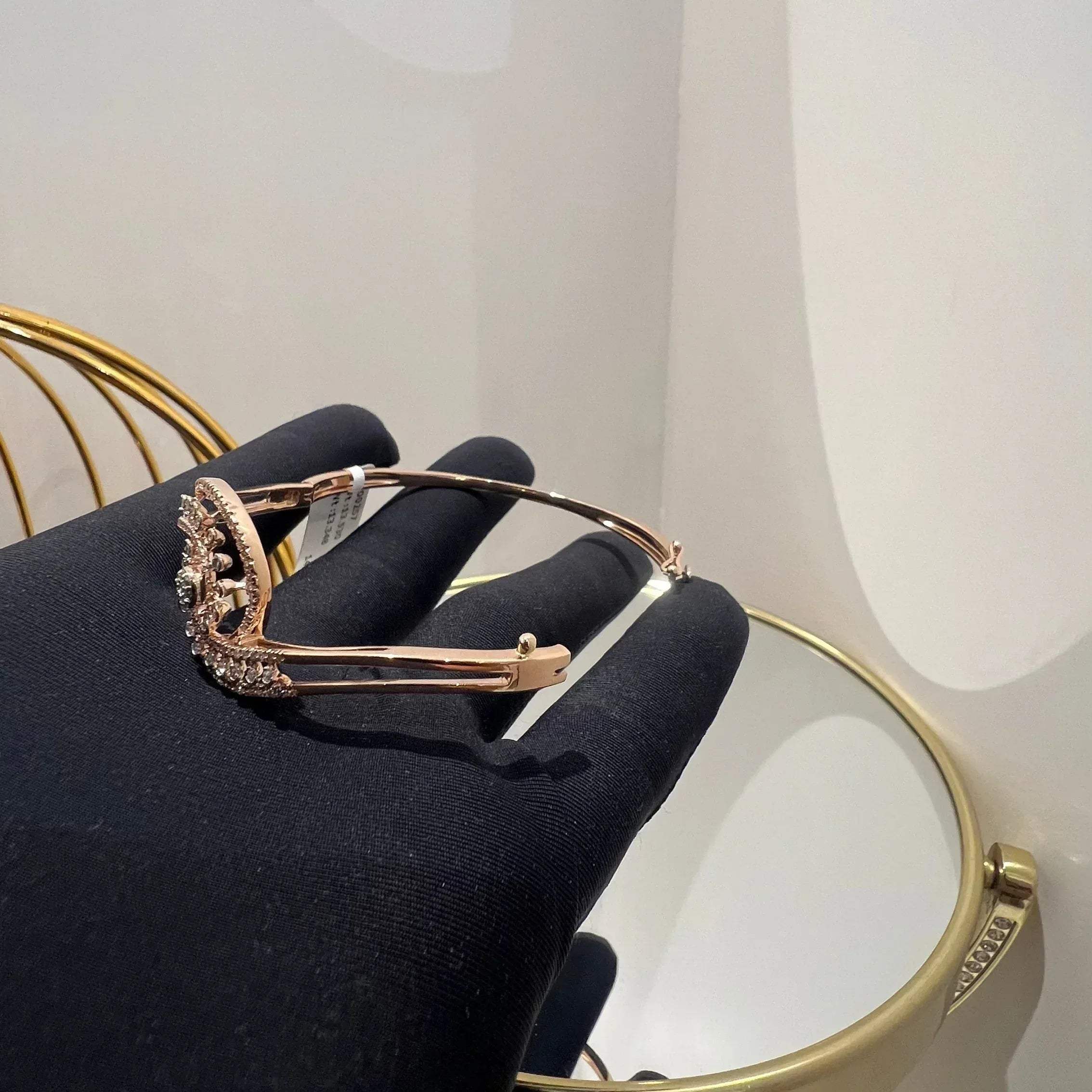 A luxurious gold diamond bracelet with a openable design, featuring a central oval-shaped diamond surrounded by smaller diamonds set in a brilliant cut, displayed on a hand.