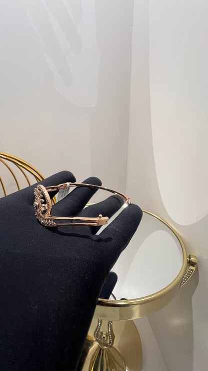 A luxurious gold diamond bracelet with a openable design, featuring a central oval-shaped diamond surrounded by smaller diamonds set in a brilliant cut, displayed on a hand.