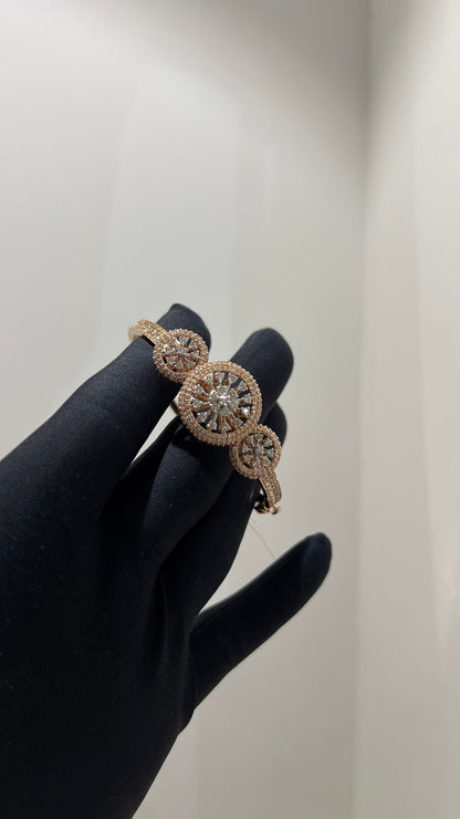 A gold diamond bracelet with a central oval-shaped diamond surrounded by smaller diamonds, displayed by a hand.