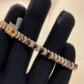A gold diamond tennis bracelet with white diamonds, held on a mannequin arm.