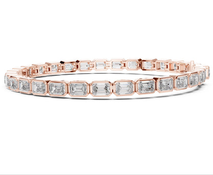 Rose gold bracelet with emerald cut real diamond accents on a white background.