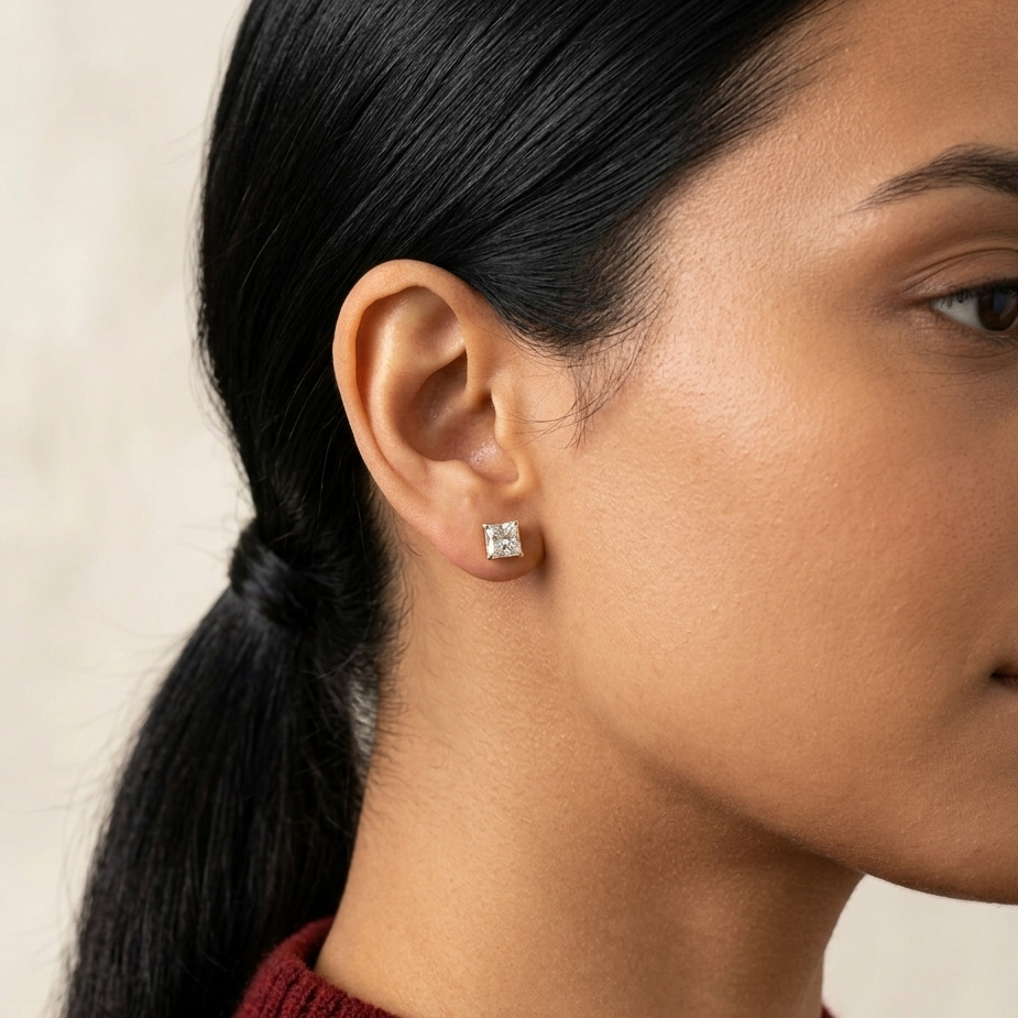 Close-up of a person wearing a diamond stud earring with a neutral background