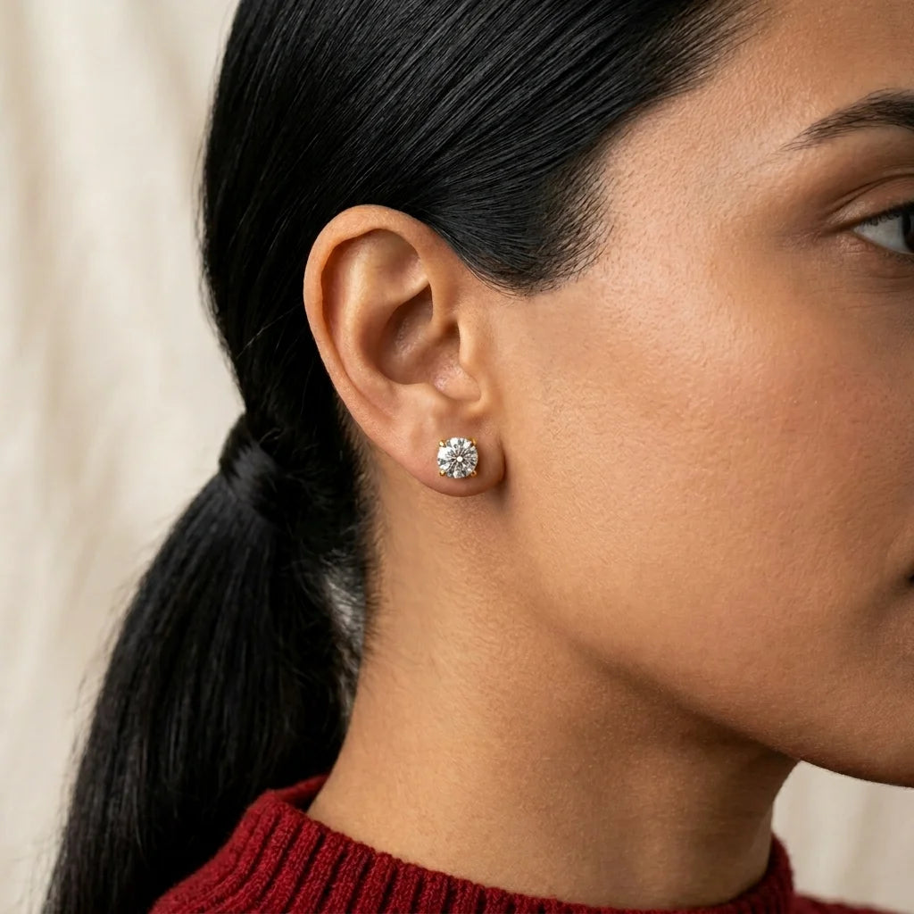 Close-up of a woman wearing a diamond stud earring with a neutral background