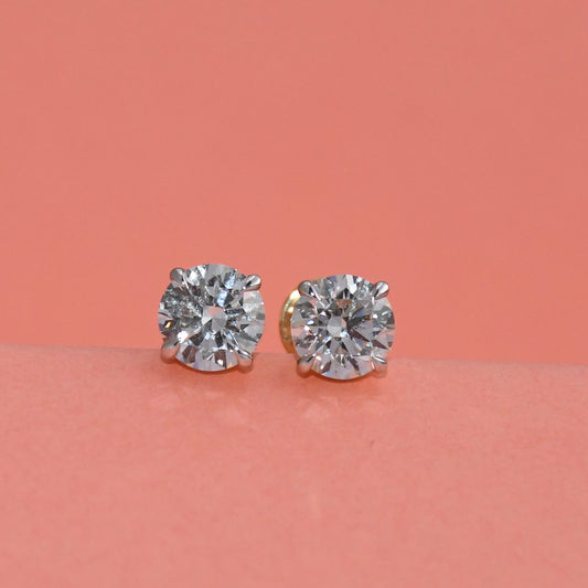 Pair of diamond stud earrings on a peach background