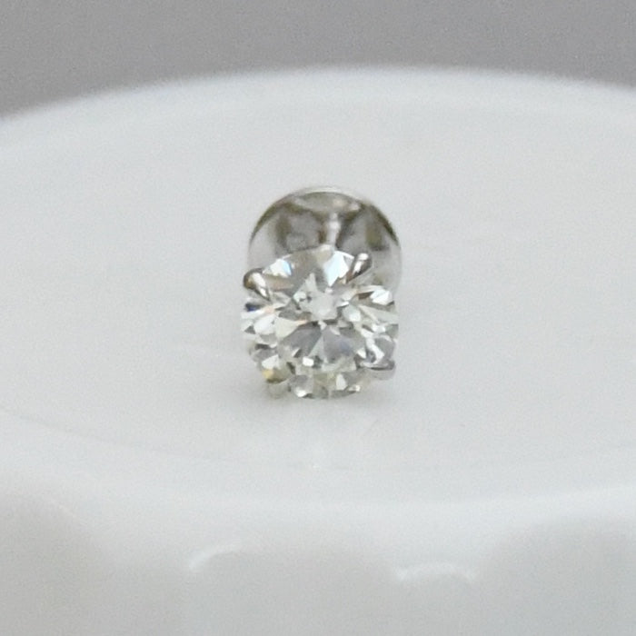 Round solitaire diamond stud earring on a light gray background