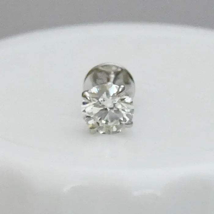 Round solitaire diamond stud earring on a light gray background