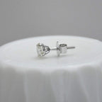white gold stud earring on a white surface with a gray background