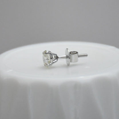 white gold stud earring on a white surface with a gray background