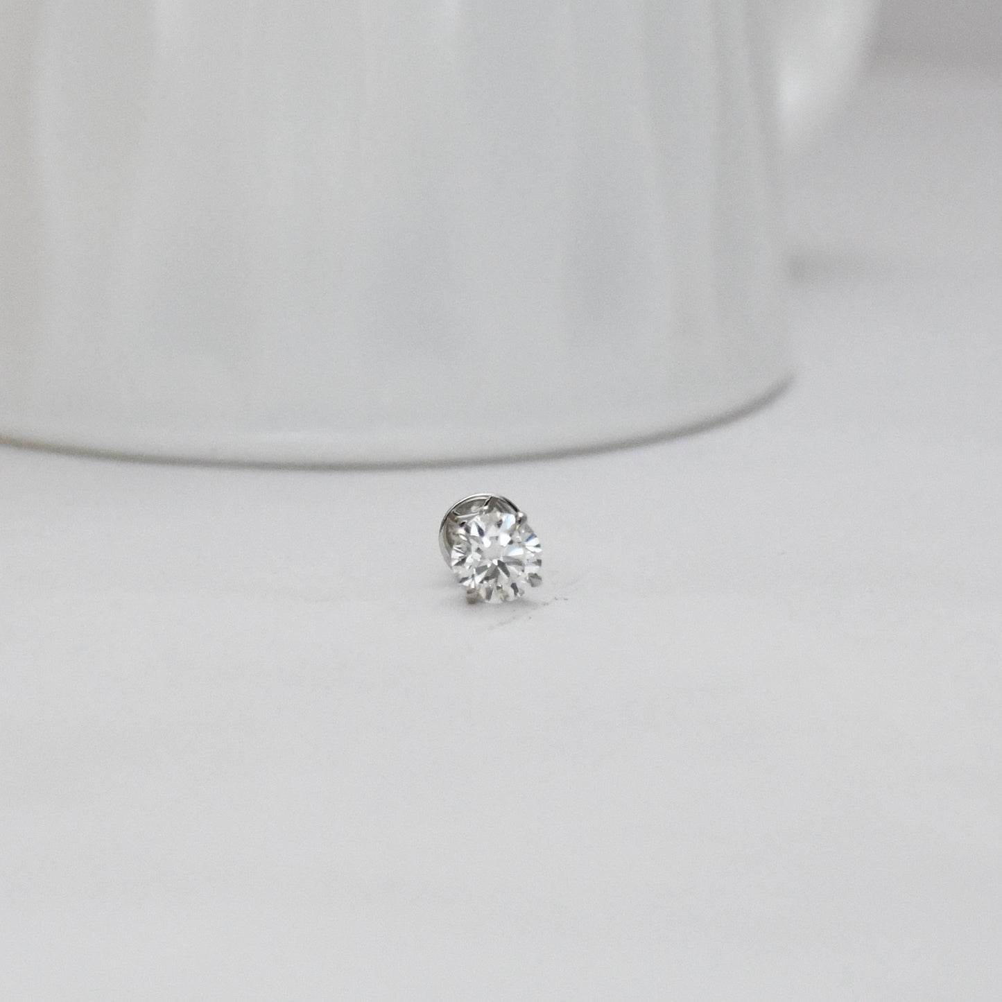 solitaire diamond stud earring on a light gray background