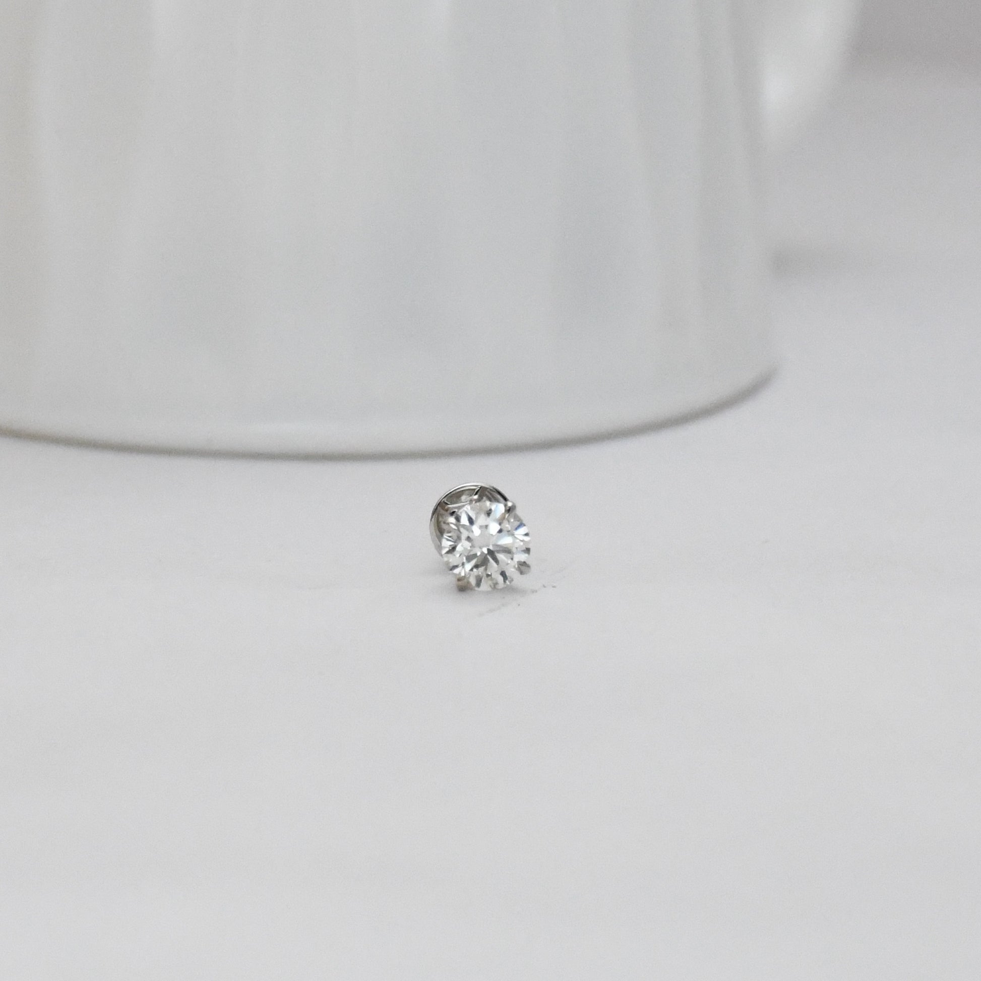 solitaire diamond stud earring on a light gray background