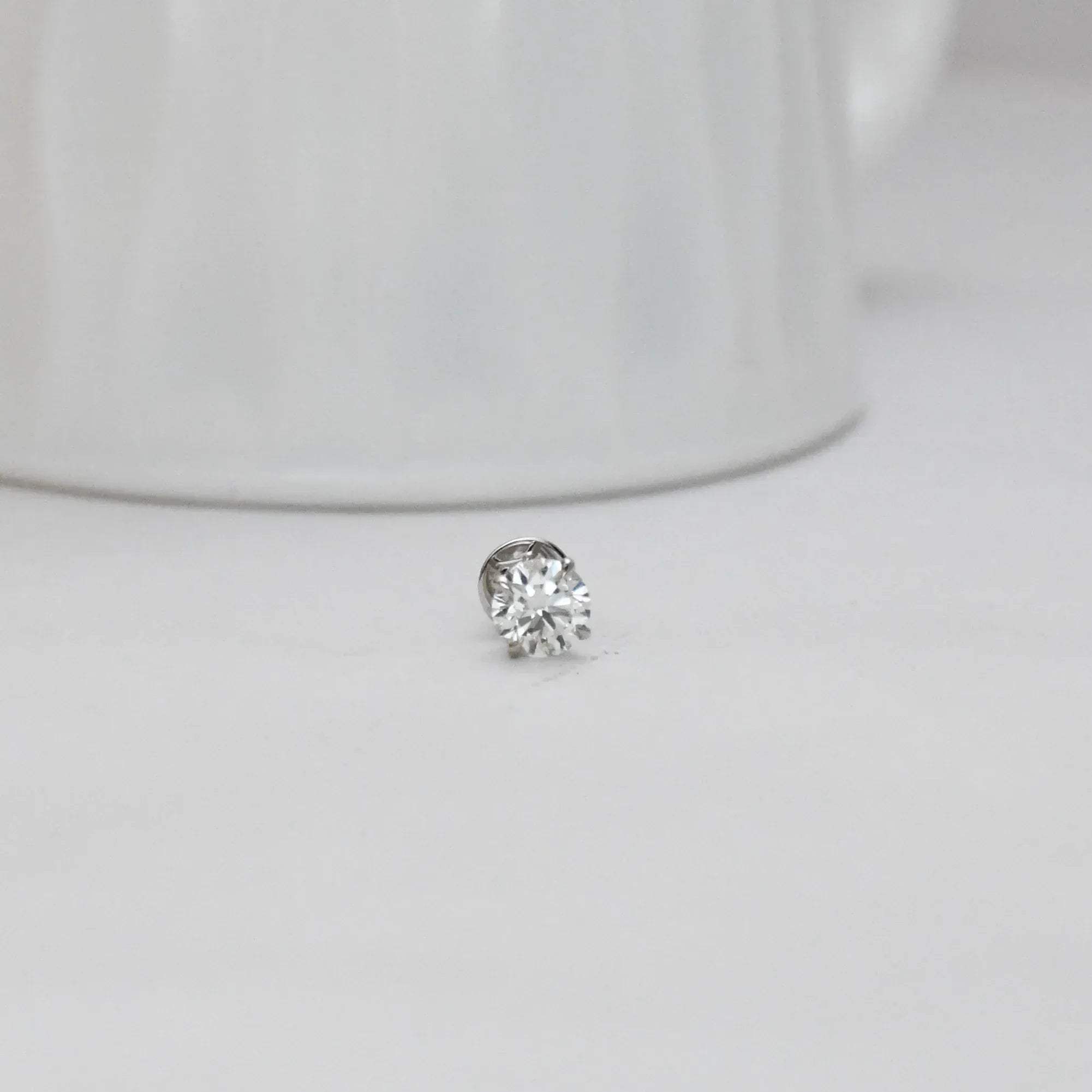 solitaire diamond stud earring on a light gray background