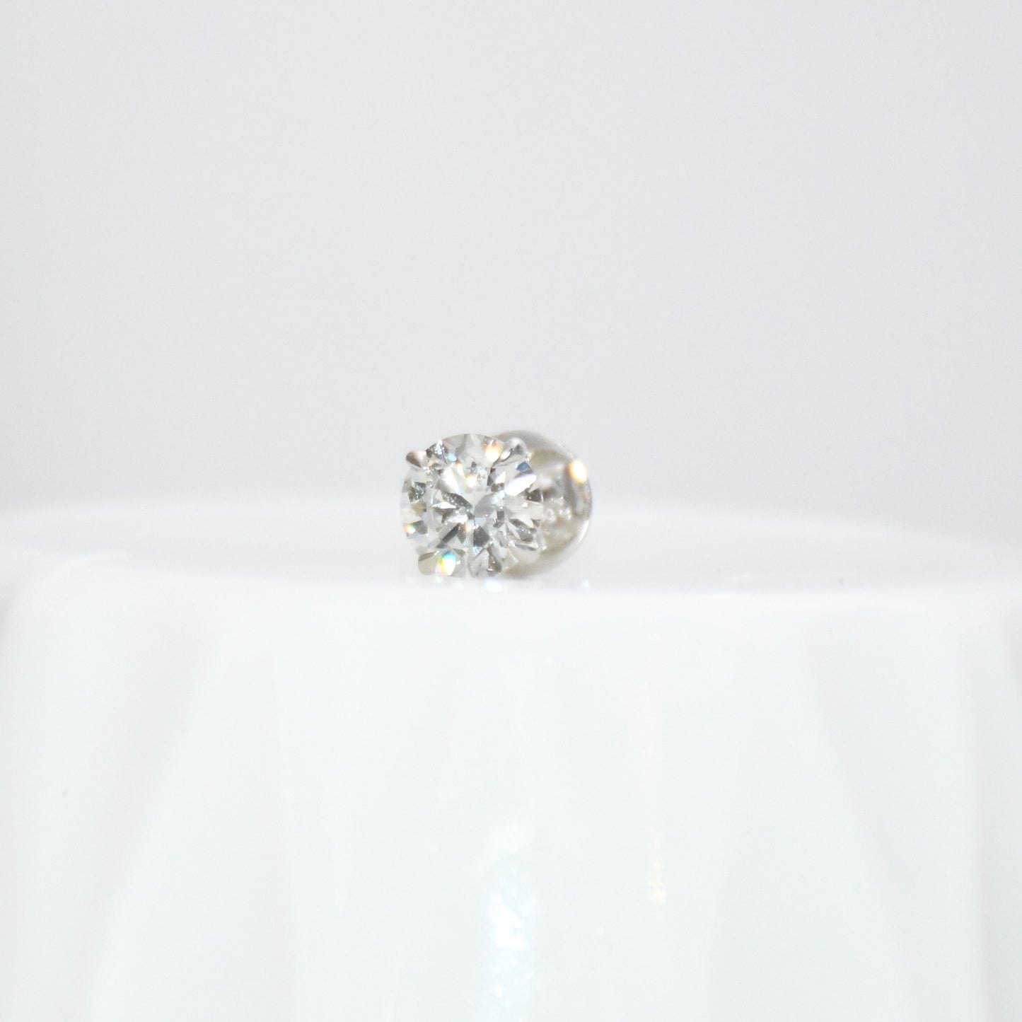 Round solitaire diamond stud earring on a white background