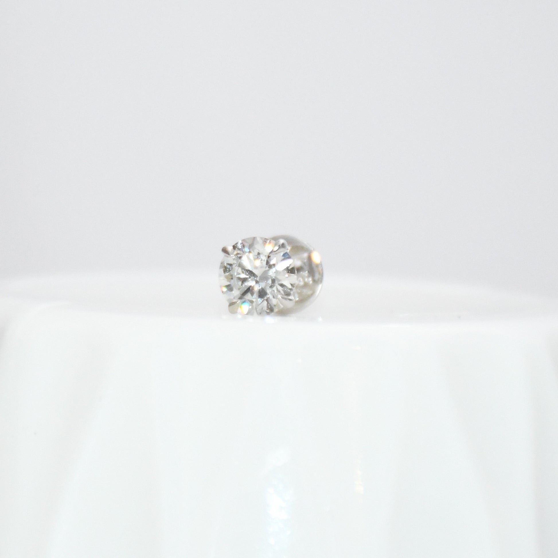 Round solitaire diamond stud earring on a white background