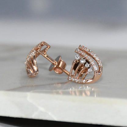 Rose gold earrings with diamond accents on a reflective surface