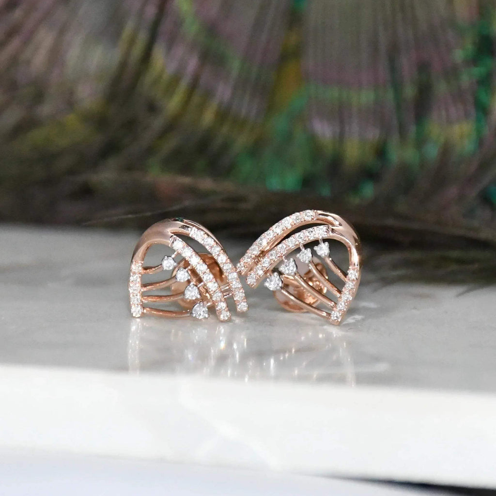 Rose gold earrings with diamond accents on a reflective surface
