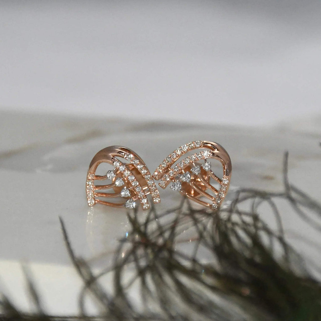Rose gold bow-shaped earrings with clear diamonds on a light background