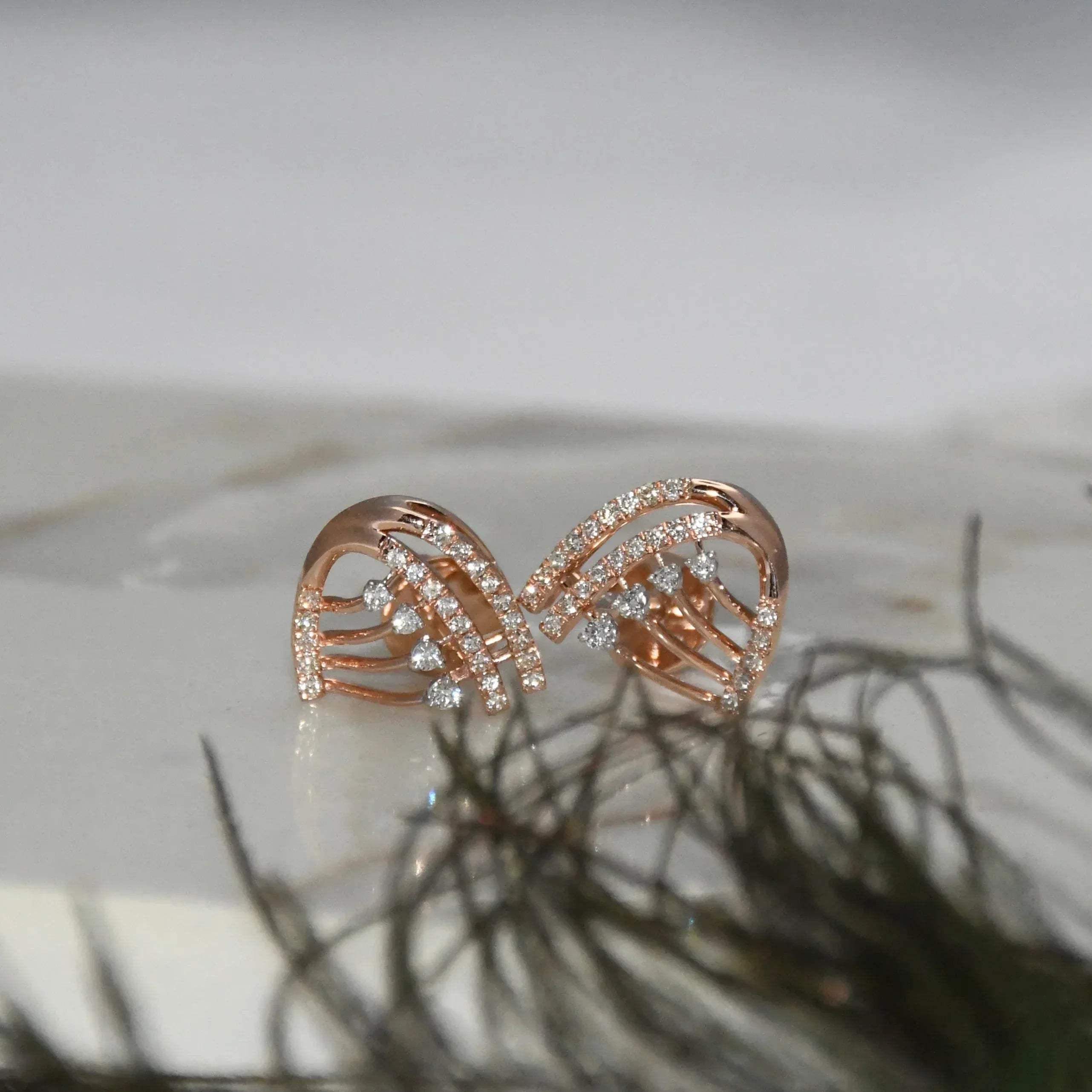 Rose gold bow-shaped earrings with clear diamonds on a light background