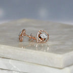 Rose gold earrings with diamond accents on a marble surface