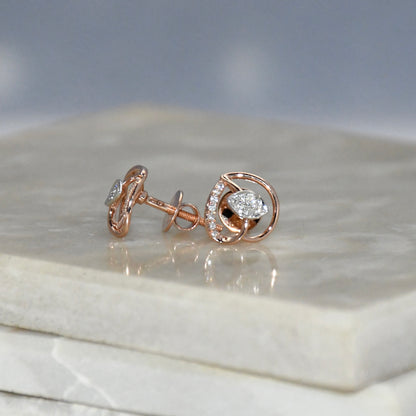 Rose gold earrings with diamond accents on a marble surface