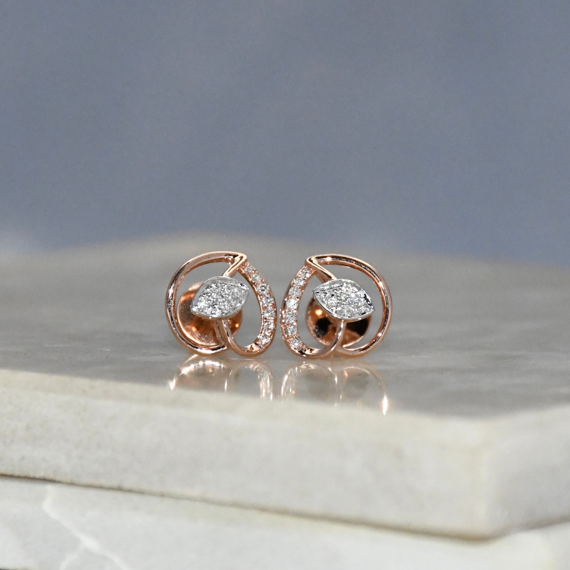 Rose gold earrings with diamonds on a marble surface