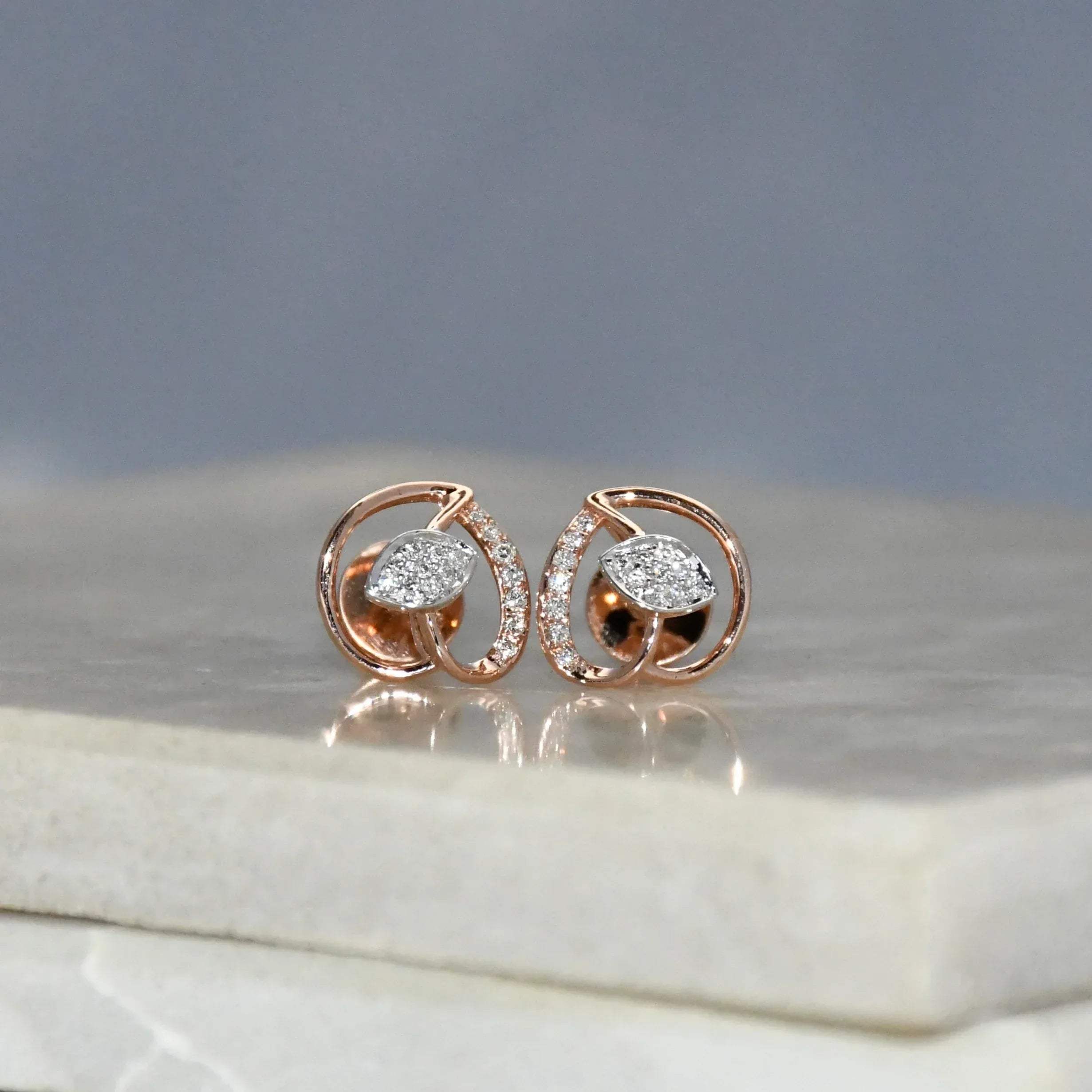 Rose gold earrings with diamonds on a marble surface