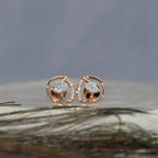 Rose gold earrings with clear diamonds on a textured surface