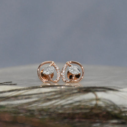 Rose gold earrings with clear diamonds on a textured surface