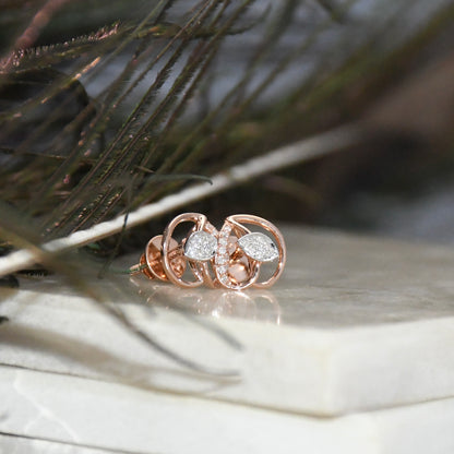 Rose gold earrings with diamonds on a wooden surface with grass in the background