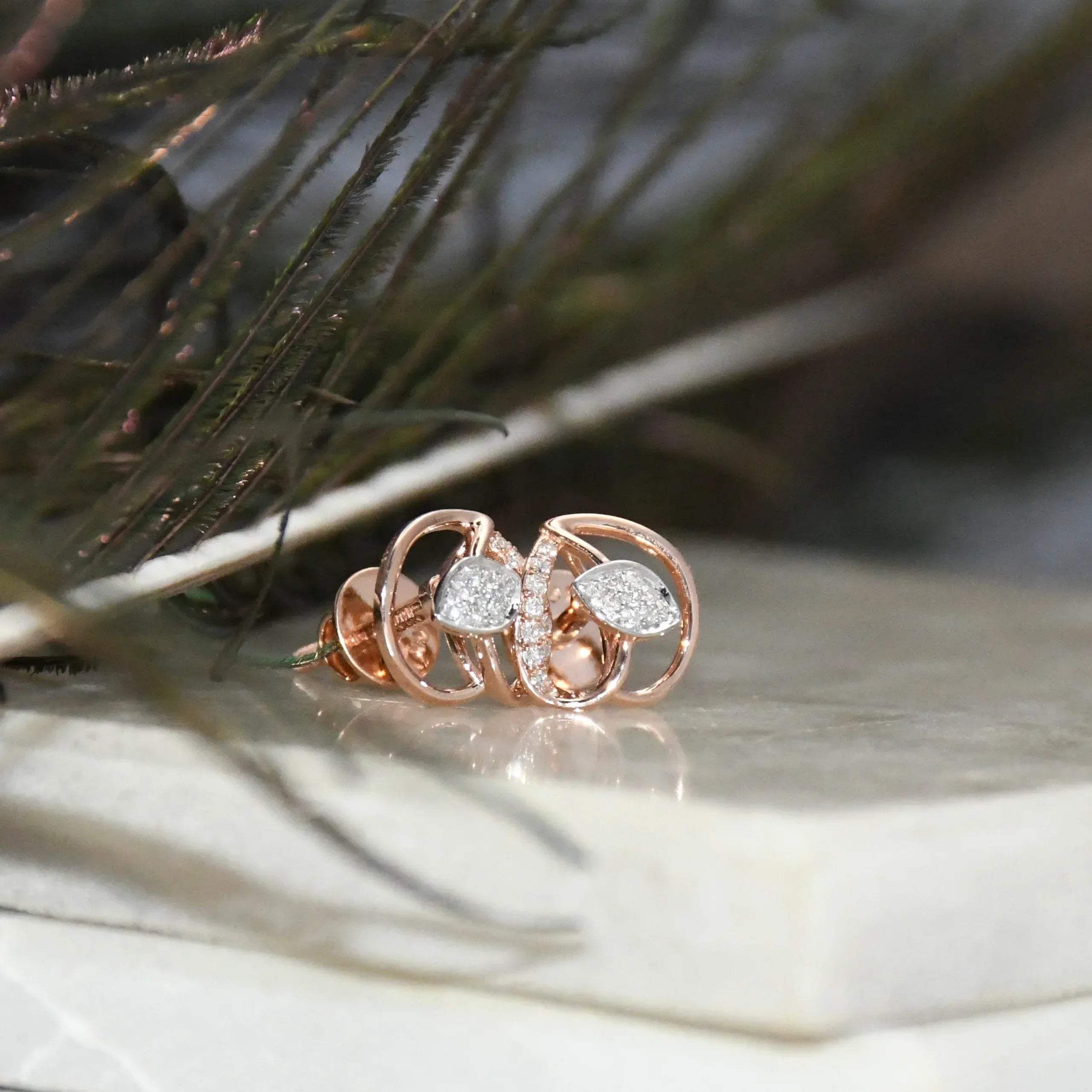 Rose gold earrings with diamond accents on a natural background
