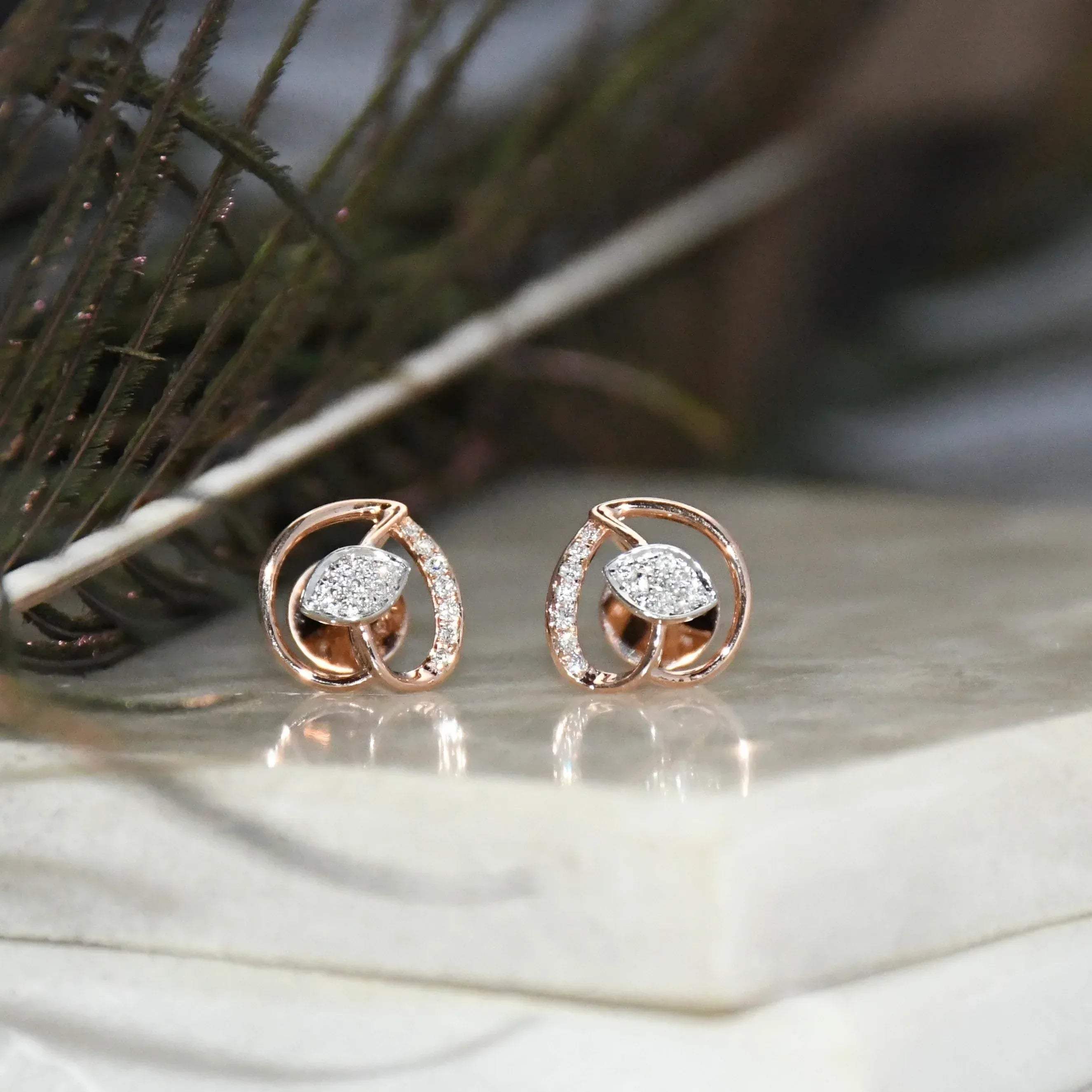 Rose gold earrings with clear diamonds on a marble surface