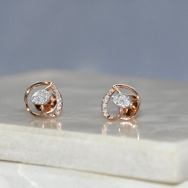 Rose gold earrings with clear diamonds on a marble surface
